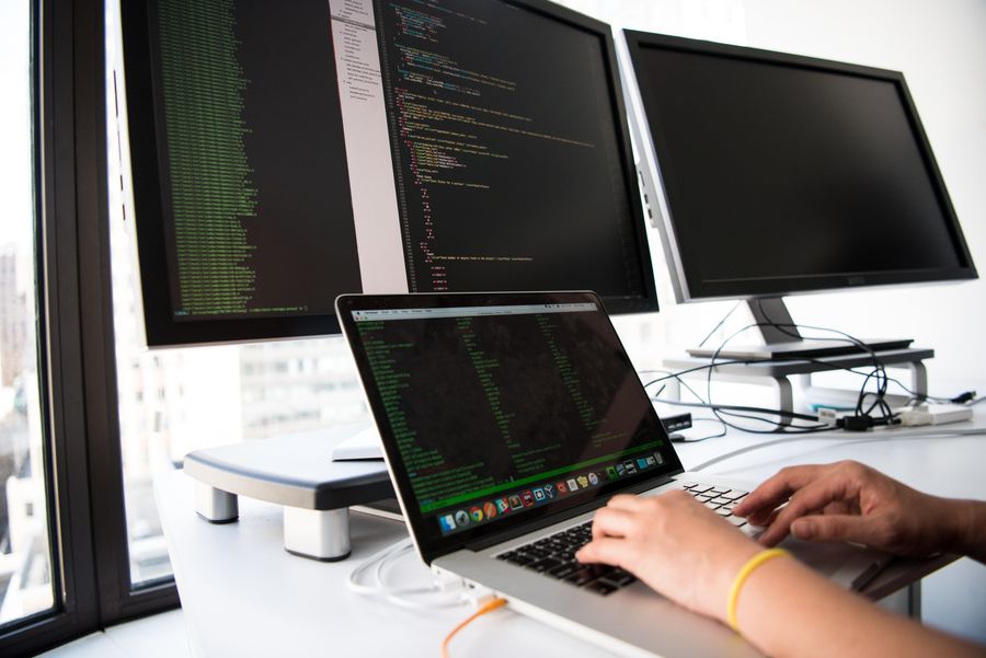 Software developer writing code on multiple screens